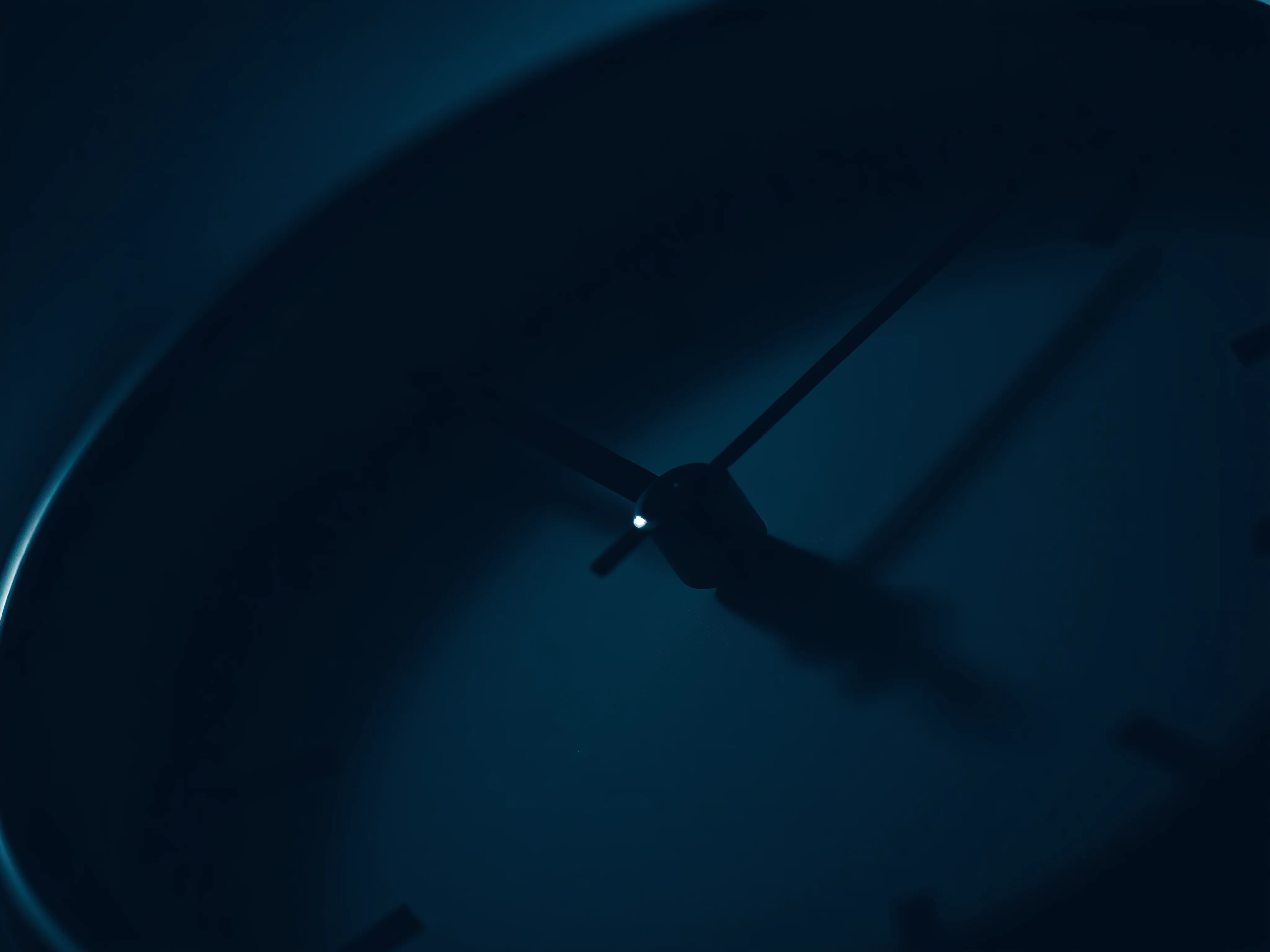 Close-up of a minimalist analog clock face at 3 AM, low-key, desaturated cool tones.